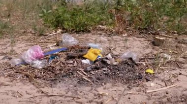 Discarded Garbage from Plastic Bottles, Plastic Bags in Sun in Forest on Sand. Garbage pit, dump, waste in nature in woods. A place for a campfire. Environmental pollution, environmental disaster.