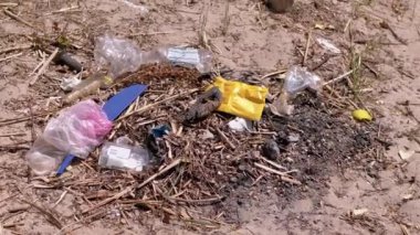 Discarded Garbage from Plastic Bottles, Plastic Bags in Sun in Forest on Sand. Garbage pit, dump, waste in nature in woods. A place for a campfire. Environmental pollution, environmental disaster.