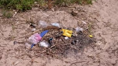 Discarded Garbage from Plastic Bottles, Plastic Bags in Sun in Forest on Sand. Garbage pit, dump, waste in nature in woods. A place for a campfire. Environmental pollution, environmental disaster.