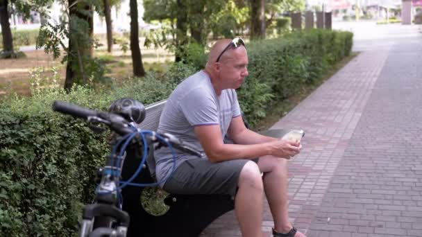 Głodny Rowerzysta Odpoczywający Ławce Jedzący Chleb Pita Świeżym Powietrzu Parku — Wideo stockowe