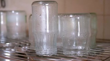 Sterilization of Glass Jars with Hot Steam on a Metal Grate at Home in Kitchen. Drops of water flowing down. Process of preparing glass containers for the preservation of vegetables for the winter.