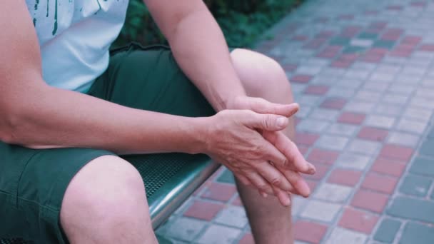 Мужчина Массирует Руки Сидя Скамейке Городском Парке Момент Ожидания Волнения — стоковое видео