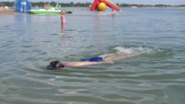 Mutlu Çocuk Yüzme, Dalış, Güneş Işıklarıyla Mavi Su Altında Nefes Tutma. Bir çocuk plajda serbest yüzmeyi öğrenir. Spor eğitimi. Sağlığa. Dinlenme, iyileşme, yaz tatili. Yaşam biçimi.