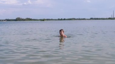 Happy Teenager is Splashing, Diving, and Having Fun in Ocean Water on the Beach. Boy learns to swim, dive underwater. Splashes of water, pleasure, joy. Family rest, recuperation, summer vacation.