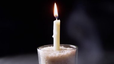 Siyah Arkaplanda, Duman Altında Yanan Beyaz Mum. Mum etrafındaki uzayda duman ve sis bulutları yükseliyor. Hafıza kavramı, ritüel, kutlama. Ağır çekim. Yakın plan..