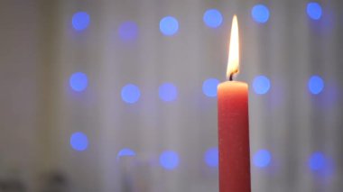 Bulanık Arkaplanda Yanan Noel Kırmızı Mum Parıldayan Çelengi. Bir çelengin üzerindeki parlak mavi, bulanık noel ışıkları. Soyut arkaplan. Parlak ışıklar. Yeni yıl arifesi. Xmas.