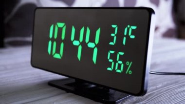 Yeşil Ekrandaki Dijital Saat 9: 44, Sıcaklık, Hava Nemi. Modern ayna saati, termometresi olan çalar saat, beyaz arka plandaki masada duran hidrometre. Zaman kavramı.
