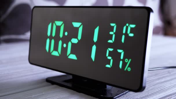 緑のディスプレイ上のデジタル時計表示時間10 空気湿度 現代のミラークロック 温度計付き目覚まし時計 白い背景に机の上に立って水分計 時間概念 — ストック動画