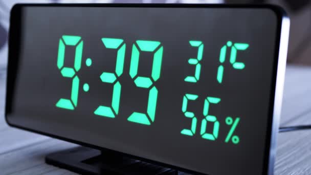 緑のディスプレイ上のデジタル時計表示時間9 空気湿度 現代のミラークロック 温度計付き目覚まし時計 白い背景に机の上に立って水分計 時間概念 — ストック動画