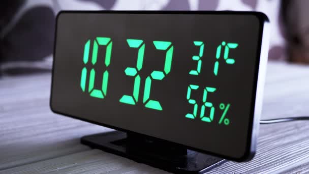 緑のディスプレイ上のデジタル時計表示時間10 現代のミラークロック 温度計付き目覚まし時計 白い背景に机の上に立って水分計 時間概念 — ストック動画