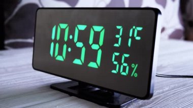Yeşil Ekran 'daki dijital saat 10: 59' u gösteriyor. Sıcaklık, hava nemi. Modern ayna saati, termometresi olan çalar saat, beyaz arka plandaki masada duran hidrometre. Zaman kavramı.