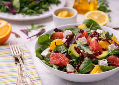 Healthy orange, avocado, grapefruit and pomegranate salad with honey and mustard dressing.