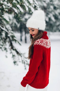 Genç bir kadın kış vakti parkta poz veriyor.