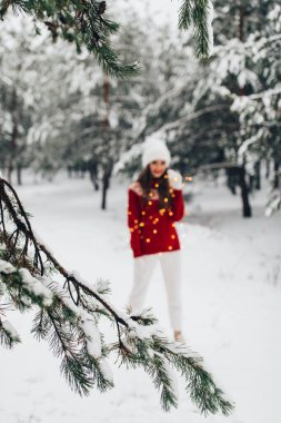Genç bir kadın kış vakti parkta poz veriyor.