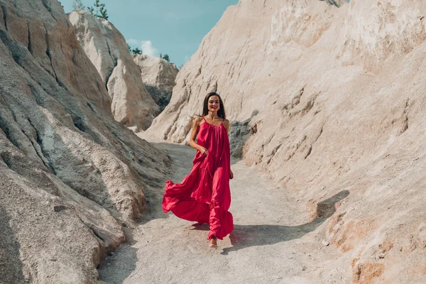 beautiful young woman in red dress posing outdoors