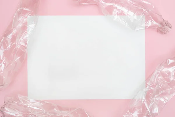 Pembe arka planda kullanılmış ve buruşmuş plastik şişeler ve mesaj için bir yer. Geri dönüşüm konsepti. Buruşuk. Makul tüketim. Düz yatıyordu. Boşluğu kopyala.