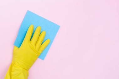 Lastik eldivenli adam pembe arka planda sarı bir bez tutuyor. İzole edilmiş. Temizlik ve yıkama için lastik eldiven. Uzayı kopyala Mesajın için yer aç. Modelleme. Yüksek kaliteli fotoğraf.