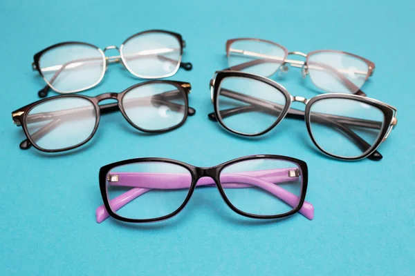 Many different glasses for vision on a blue background. Group of glasses with lenses for vision correction. Vision problems — Stock Photo, Image