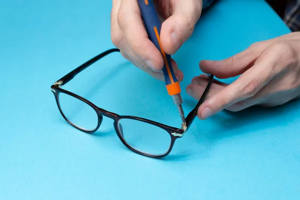 Master tightens the bolt on the glasses. Eyeglass frame repair. Optics salon and repair shop