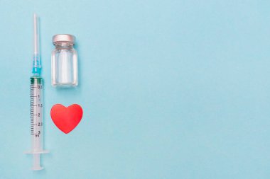 Şırınga, kalp, covid 19 aşı ve mavi arka planda tıbbi maske. Sağlığına dikkat et. Aşılama. Tıbbi tedavi konsepti. Düz yatıyordu. Dokunulmazlık. Uzayı kopyala Metin için yer.