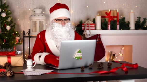 Babbo Natale ha iniziato a preparare i regali di Natale. Digita su un computer portatile. — Video Stock