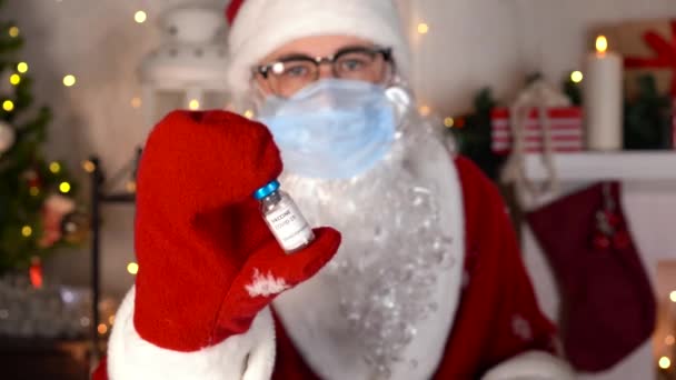 Babbo Natale in maschera protettiva medica blu contiene il flaconcino di vaccino coronavirus covid — Video Stock