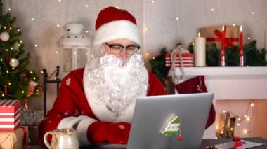 Noel Baba Noel hediyeleri hazırlamaya başladı. Dizüstü bilgisayarda yazıyor. Yavaş çekim