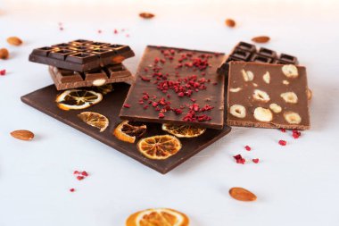 Doğal organik süt ve çikolatalı süblimleşmiş böğürtlen, portakal dilimleri, badem ve fındıklı beyaz arka plan. Şekerleme malzemeleri. Yan görünüm.