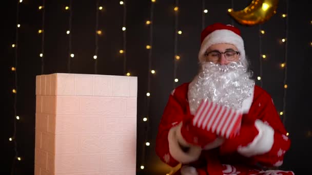 Santa lanza regalos de Navidad en el aire y lo pone en la chimenea de la casa. — Vídeos de Stock