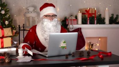 Noel Baba bir mektup okuyor ve Noel atölyesinde dizüstü bilgisayarda yazıyor..