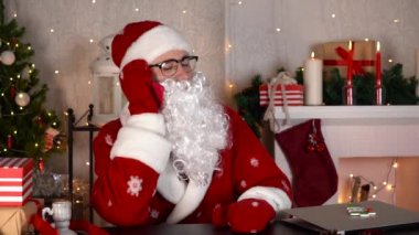 Noel Baba cep telefonuyla konuşuyor ve gülümsüyor. Yavaş çekim.