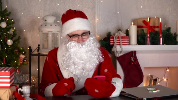 Le Père Noël lit les nouvelles sur les réseaux sociaux. Le Père Noël est surpris par les nouvelles. — Video