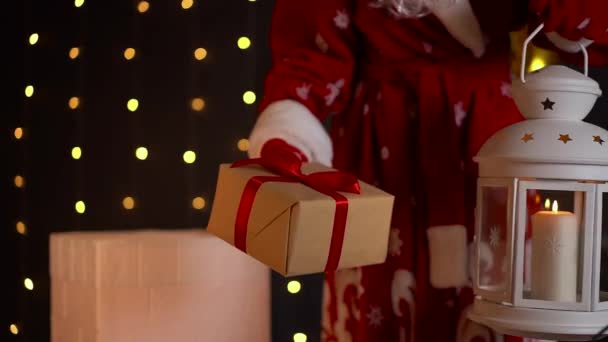 Santa with candle lamp puts Christmas gift into the house chimney. Magical night — Stock Video