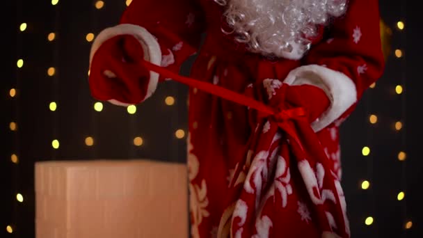 Santa Claus desata cinta roja en el bolso con regalos de Navidad. Feliz Navidad.. — Vídeos de Stock