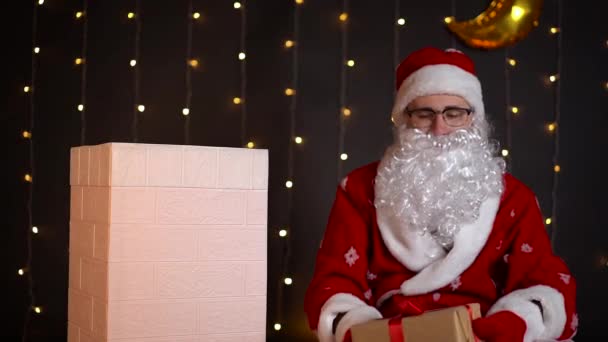 Weihnachtsmann wirft Weihnachtsgeschenke in die Luft und steckt sie in den Kamin des Hauses. — Stockvideo