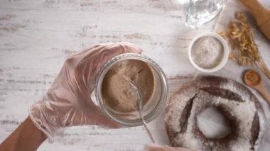 Şef ev yapımı çavdar ekmeğini kavanozda ekmek yapmak için kaşıkla karıştırıyor. Üst görünüm.