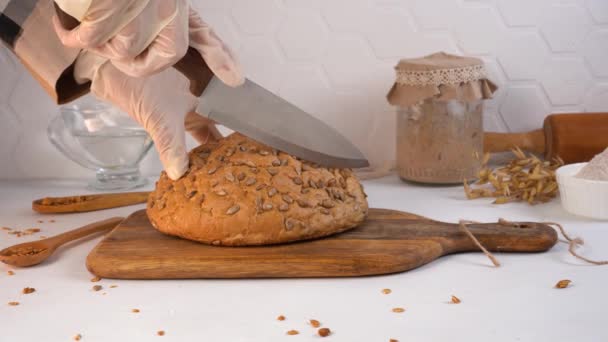 Кухар вирізає домашній хліб. Смажений у банці на фоні. Крупним планом . — стокове відео