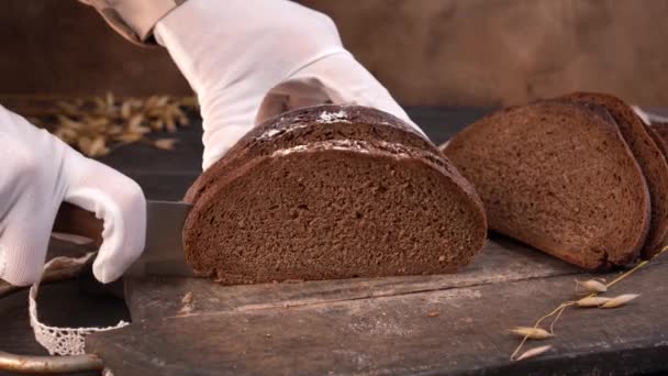 Ο σεφ κόβει σπιτικό ψωμί σε φέτες με κουζινομάχαιρο. Κοντινό πλάνο. — Αρχείο Βίντεο