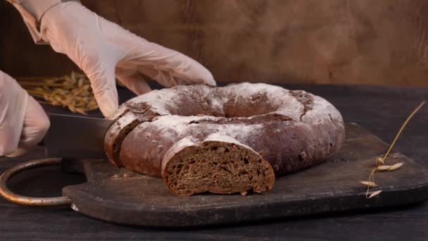 Ο σεφ κόβει σπιτικό καρβέλι ψωμί σε φέτες με κουζινομάχαιρο. — Αρχείο Βίντεο