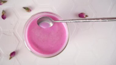 Pembe gül sütü. Sıcak sütü kaşıkla karıştırıyorum. Bir bardak ay sütü. Sağlıklı içecek.