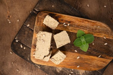 Geleneksel doğu tatlıları halva ile ayçiçeği tohumları ve nane yaprakları kesme tahtasında. Ahşap arka plan. Üst görünüm.