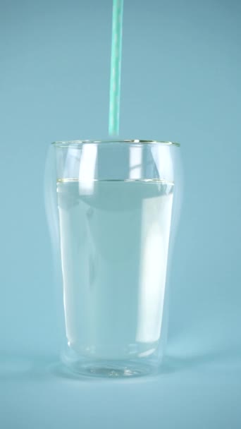 Двухстенный стакан чистой воды с голубой соломинкой. Медленное движение. — стоковое видео