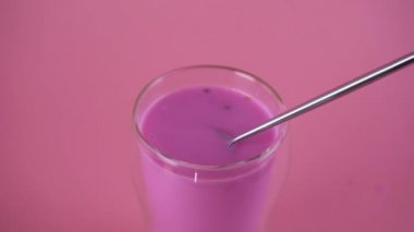 Pembe gül sütü. Sütü kaşıkla karıştırıyorum. Bir bardak ay sütü. Yavaş çekim.