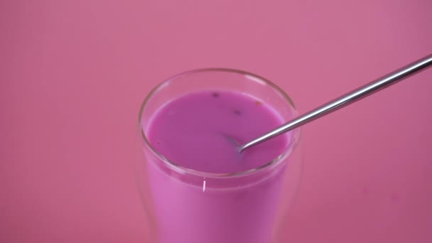 Rosa de leche de rosa. Mezclar la leche con una cuchara. Un vaso de leche de luna. Movimiento lento. — Vídeos de Stock