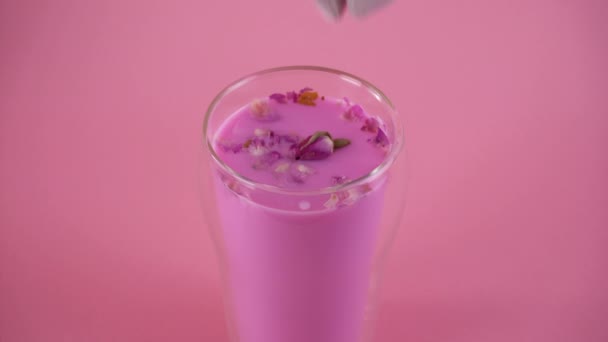 Rosa de leche de rosa. Añadiendo brotes de rosa a un vaso de leche de luna. Bebida saludable. — Vídeos de Stock