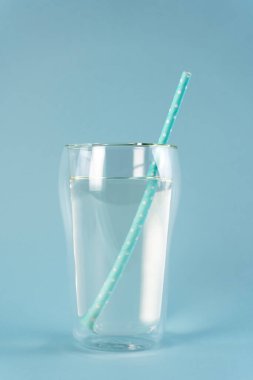 Mavi pipetli bir bardak saf su. Dikey yönelim.