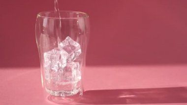 Tatlı su, çift katlı bir bardağa buz küpleriyle doldurulur. Yavaş çekim.