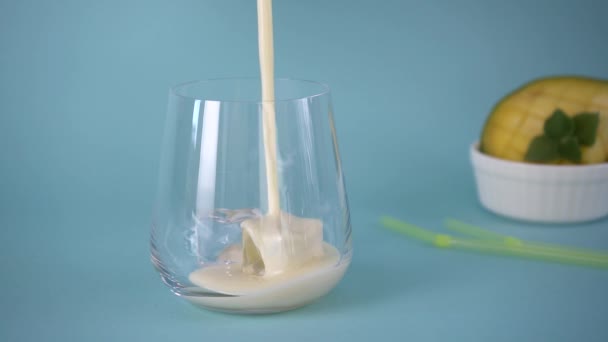 Traditionele Indiase mango lassi wordt gegoten in een glas met ijs. Langzame beweging. — Stockvideo