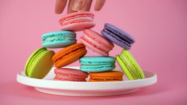 Las manos de las mujeres toman deliciosos macarrones franceses coloridos del plato. 8 de marzo. — Vídeo de stock