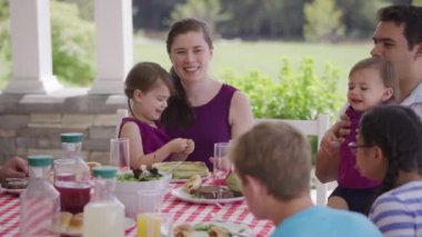 Bir grup insan arka bahçede barbekü yiyor ve eğleniyor.